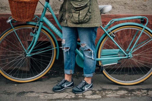 Lady standing beside a bike in the street