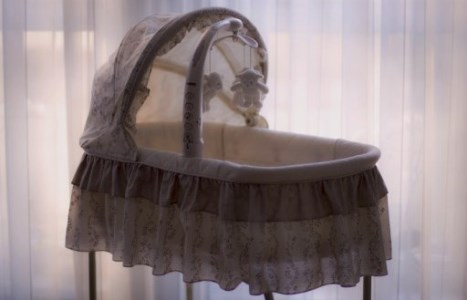 Baby cradle in front of white sheer curtain