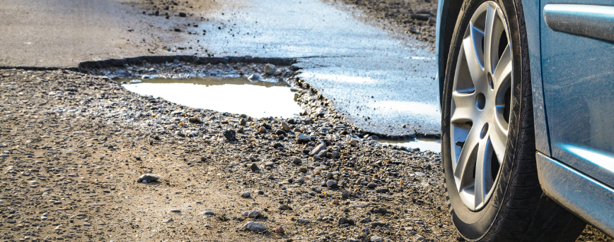 Pothole on a road with a tire wheel