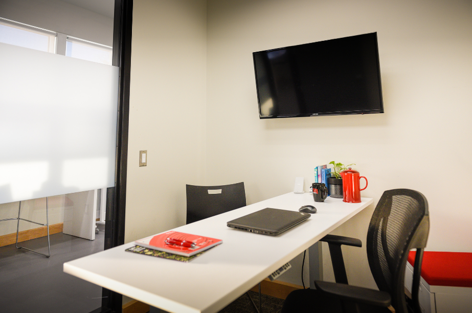 Private office with desk, chair, mounted television monitor and notebooks within Venture13 VentureZone
